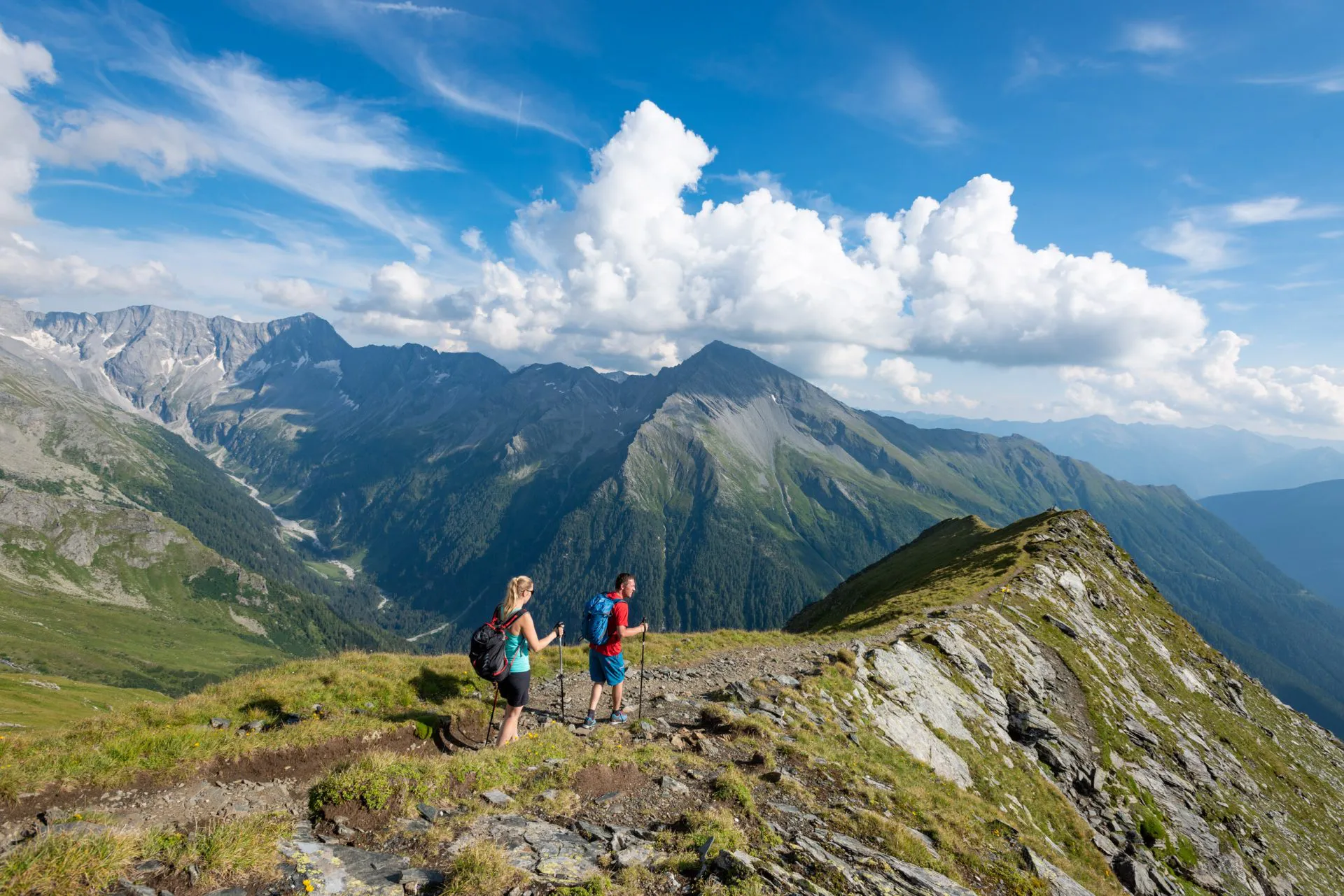 Wanderpaar auf einem Gratweg mit Blick auf die Hohen Tauern